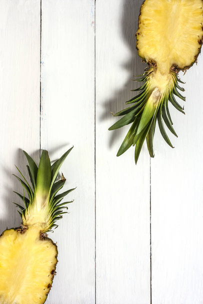 Две половинки сочного нарезанного ананаса на белом деревенском фоне. Минимальная фруктовая концепция
 - Фото, изображение