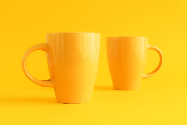 Two yellow coffee cups on yellow background, coffee break and caffeine addiction concept - Fotó, kép