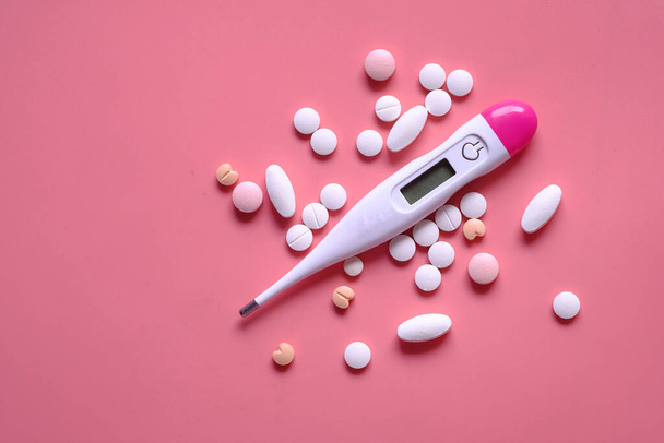 close up of pills and thermometer on pink background  - Φωτογραφία, εικόνα