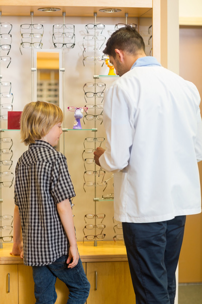 Optometrista y niño eligiendo gafas en la tienda
 - Foto, imagen