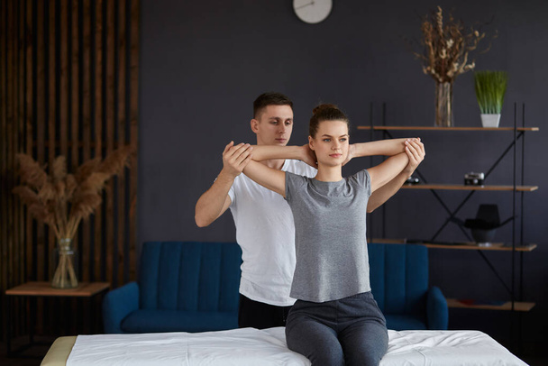 Female patient doing physical exercises with physiotherapist. Male therapist treating injured neck of young athlete. Post traumatic rehabilitation, sport physical therapy, recovery concept - Photo, image