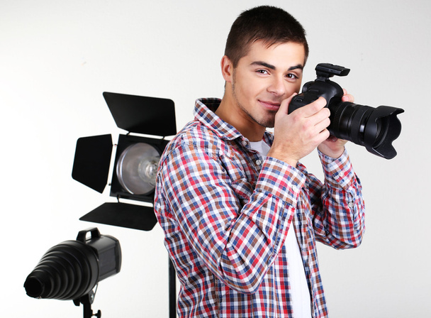 Handsome photographer with camera, on photo studio background - Fotó, kép
