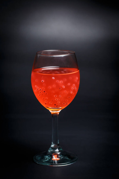Tasty red cocktail with grains on a black background - Foto, afbeelding