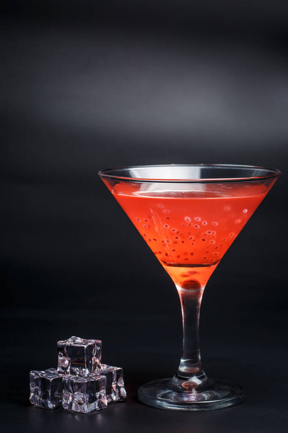 Tasty red cocktail with grains on a black background - Foto, afbeelding