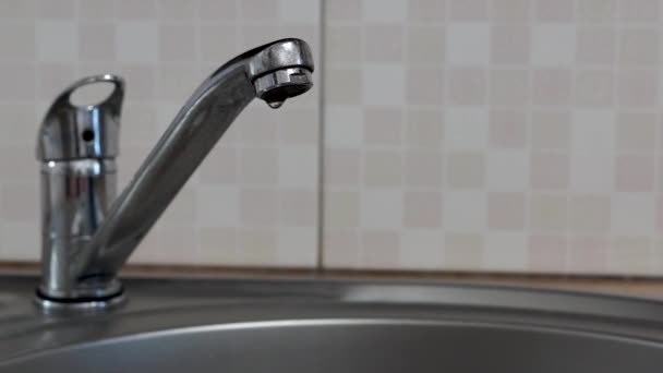 Νερό στάζει σε στρογγυλό μεταλλικό νεροχύτη κουζίνας από διαρροή βρύση βρύσης - Πλάνα, βίντεο