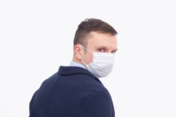 Portrait of a man on a white isolated background, face covered with a medical mask, banner for text. Health, awareness, and timeliness. Healthy lifestyle. No viruses. - Photo, image