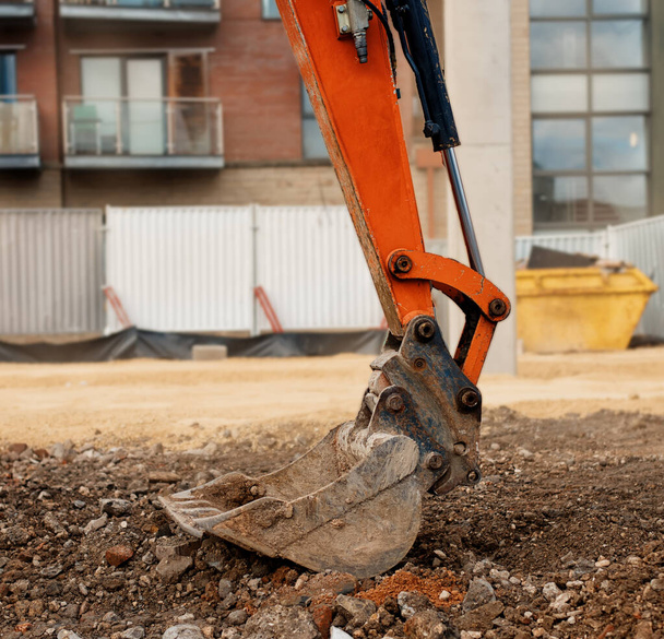 Primer plano de un cucharón de excavadora naranja colocado en el suelo en posición segura
   - Foto, Imagen