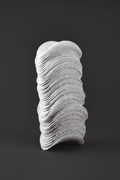 Stack of potato chips in dark background, black and white. Minimalistic image of attention grabbing fast food low-key - Foto, Bild