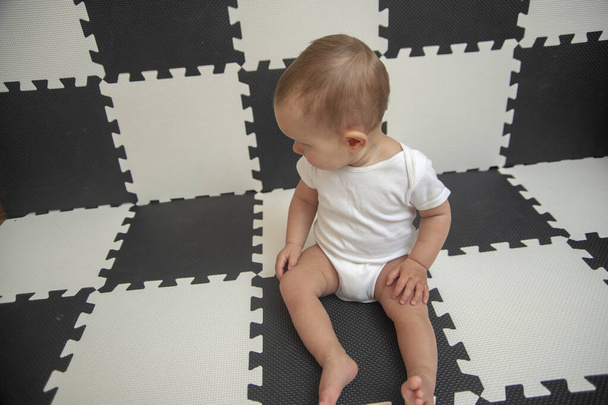 Beyaz giysili bebek siyah-beyaz arka plana bakıyor.. - Fotoğraf, Görsel