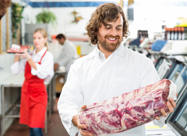 Happy Butcher Looking At Meat Package - 写真・画像