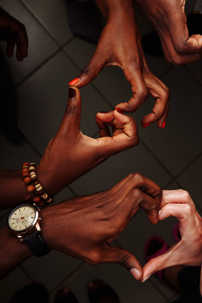 Manos en forma de corazón de un grupo feliz de personas multinacionales africanas, latinoamericanas y europeas que permanecen juntas en círculo
 - Foto, Imagen