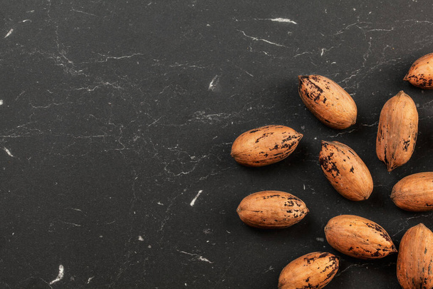 Whole pecan nuts on black marble like board, space for text left, overhead photo - Fotoğraf, Görsel