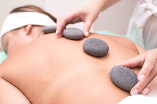 close up view of spa procedure on color back Retrato de uma jovem mulher desfrutando alegremente de terapia termal. close-up. Pedras de massagem
 - Foto, Imagem
