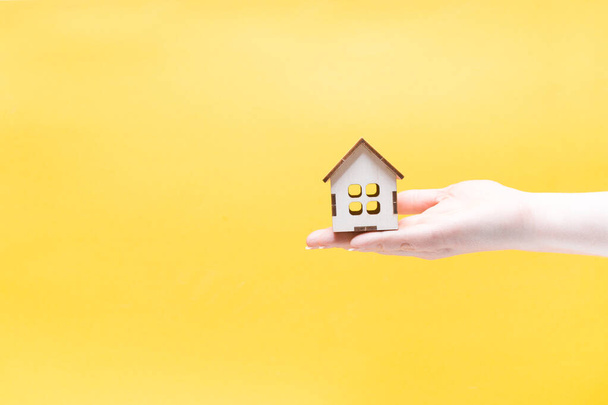 wooden house in the palm of your hand, yellow office copy space, sales real estate purchase concept, house rental, country construction - 写真・画像
