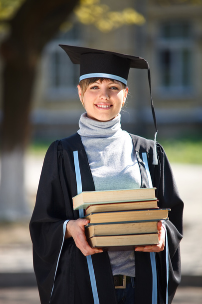 Porträt einer jungen Absolventin mit einem Stapel Bücher - Foto, Bild