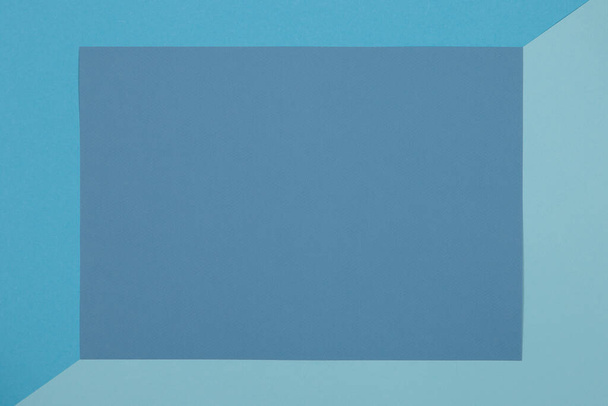 Blue background, colored paper geometrically divides into zones, frame, copy space. - Foto, Imagen
