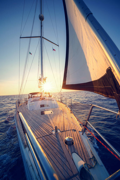 Фотографія дерев'яної яхти у стилі ретро на відкритому морі. Довга подорож на яхті краси на заході сонця
. - Фото, зображення