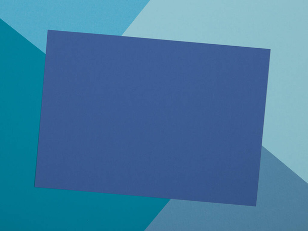 Blue background, colored paper geometrically divides into zones, frame, copy space. - Фото, зображення