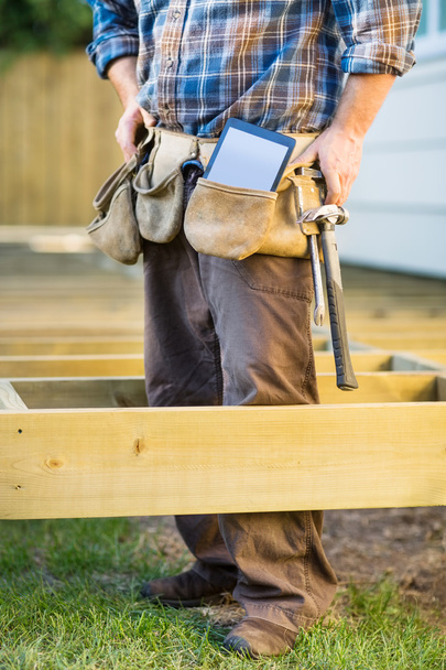 Carpenter With Tablet Computer And Hammer In Tool Belt - Foto, afbeelding
