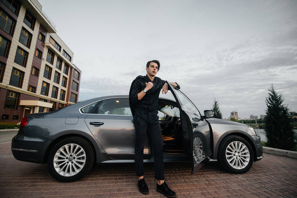 A stylish businessman smokes cigars near a luxury car. Fashion and business - Φωτογραφία, εικόνα