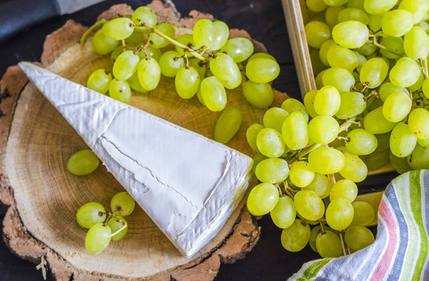 Brie sajt és fehér friss szőlő fából készült táblán - Fotó, kép