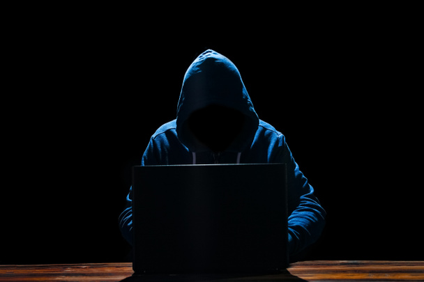Хакер с ноутбуком за столом проникает в систему
 - Фото, изображение