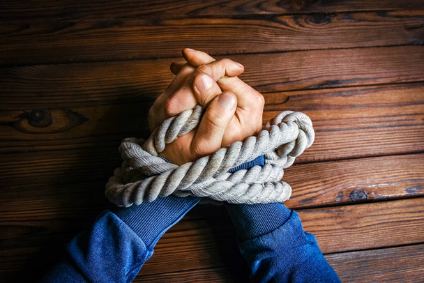 hands with a rope on a wooden background - Фото, изображение