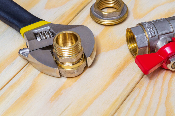 Klempnermontage und verstellbarer Schraubenschlüssel auf einem Holzbrett bei Reparatur oder Austausch von Ersatzteilen - Foto, Bild