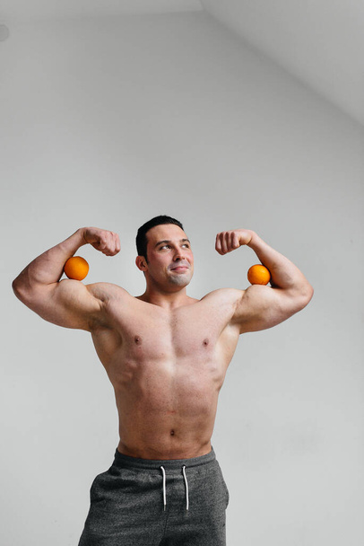 Deportivo chico sexy posando sobre un fondo blanco con frutas brillantes. Dieta. Dieta saludable - Foto, imagen