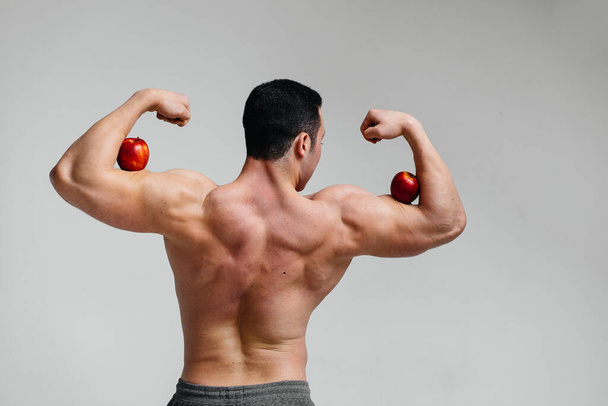 Sporty sexy guy posing on a white background with bright fruits. Diet. Healthy diet - Photo, Image