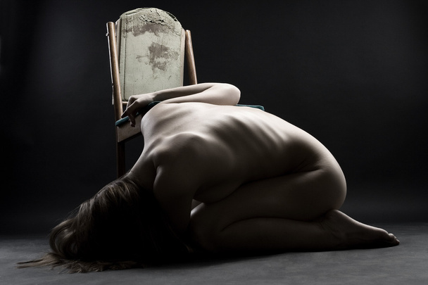 Молодая голая женщина свернулась калачиком на полу в горе
 - Фото, изображение