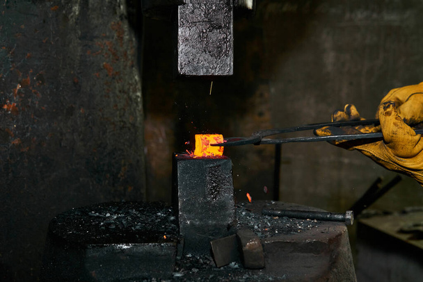 Metallkünstlerin bearbeitet in Werkstatt ein glühendes Werkstück mit einem Presslufthammer - Foto, Bild