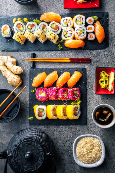 vrchní pohled na lahodné sushi set na břidlicové desky s hůlkami - Fotografie, Obrázek