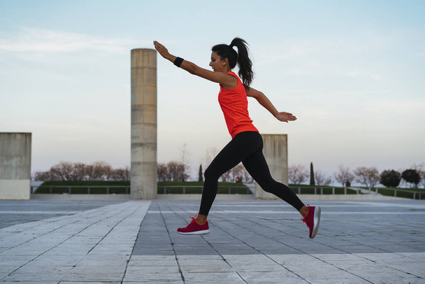 Jonge fitte vrouw die springt bij zonsondergang. Fitness en gezonde levensstijl - Foto, afbeelding