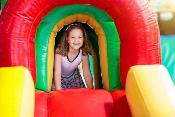 Kind springt auf buntem Spielplatz-Trampolin. Kinder hüpfen auf der Kindergeburtstagsfeier in der Hüpfburg. Kleiner Junge spielt im Sommer draußen. - Foto, Bild