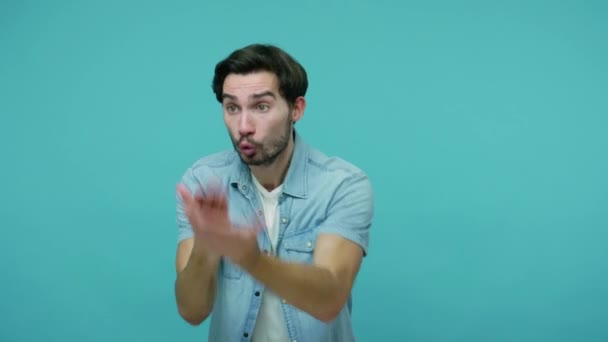 Anxious worried bearded guy in jeans shirt gesturing facepalm, expressing regret and sorrow over defeat, sports fan upset by loss of his beloved team. studio shot, isolated on a blue background. - Кадры, видео
