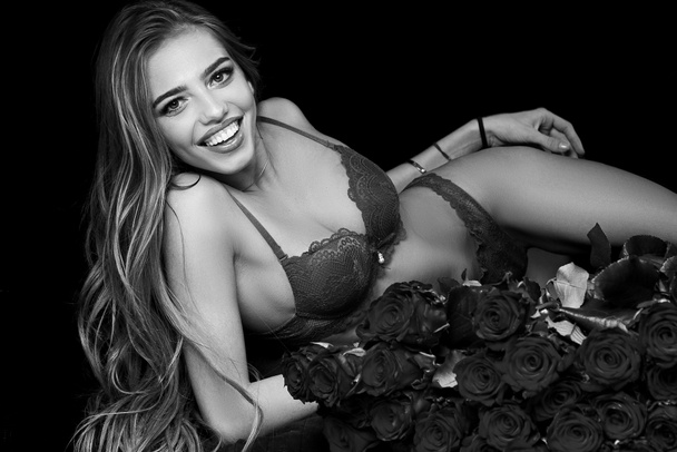 Girl and rose. Sexy beautiful woman holding large bouquet of red roses on black background. Beautiful woman with red roses. Valentines day. Valentine. - Фото, изображение
