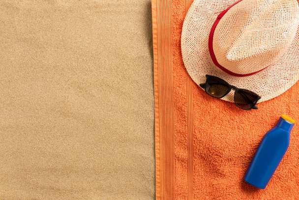 Summer vacation composition. Straw hat, sunglasses and sun cream on sand background - Foto, Imagem