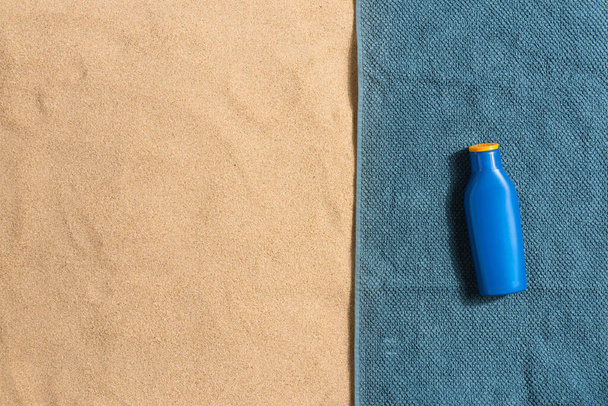 Summer vacation composition. sun cream on sand background. Border composition made of towel. Harsh light with shadows - Foto, Imagem