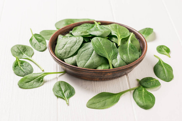 A large number of spinach leaves on a white wooden table. Food for fitness. The view from the top. - Fotoğraf, Görsel