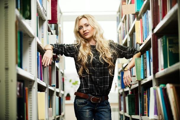 Молода красива блондинка в бібліотеці
 - Фото, зображення