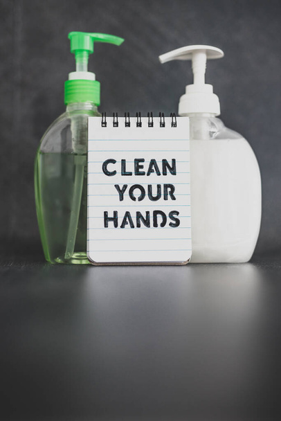 keep your hands clean to fight bacteria and viruses conceptual still-life, hand sanitizer and liquid soap next to memo with Clean your Hands text - Photo, image