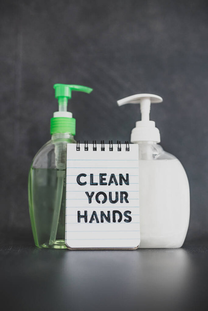 keep your hands clean to fight bacteria and viruses conceptual still-life, hand sanitizer and liquid soap next to memo with Clean your Hands text - Фото, изображение