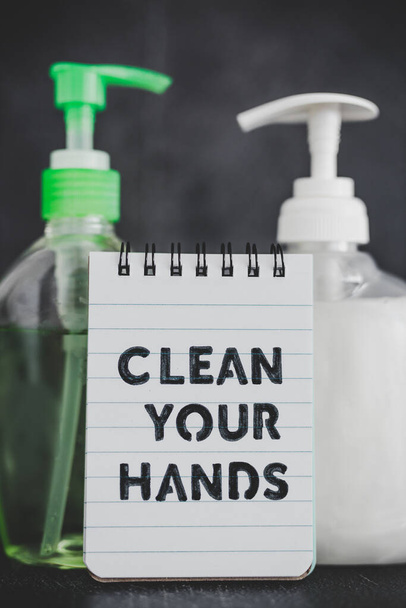 Держите руки чистыми, чтобы бороться с бактериями и вирусами концептуальный натюрморт, дезинфицирующее средство для рук и жидкое мыло рядом с памяткой с Чистить руки текст
 - Фото, изображение
