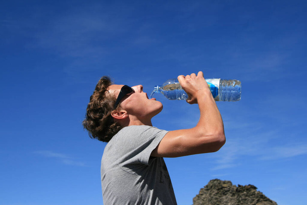 Young man drinks from water bottle - Foto, Imagen