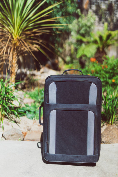 concept of summer holidays, suitcase with tropical garden bokeh behind it concept of travelling to warm tropical destinations - Φωτογραφία, εικόνα