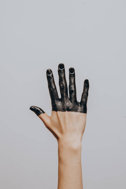 Elegant female hand dipped in black paint on a light background. Isolated. Gesture. - 写真・画像