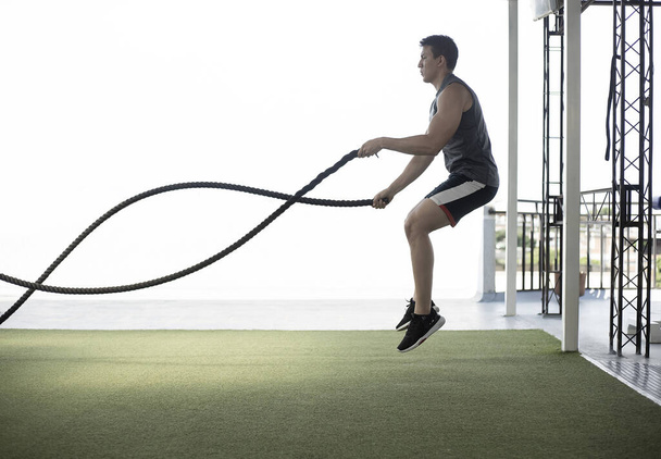 man jumping with cross fit rope whit foreground white - Photo, Image