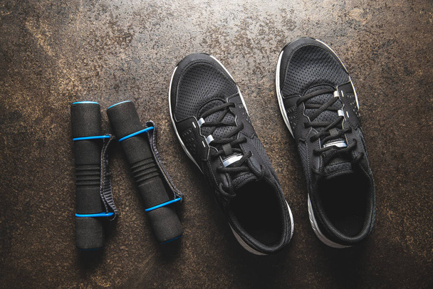 Fitness concept. Black sports shoes and dumbbells. Top view. - 写真・画像