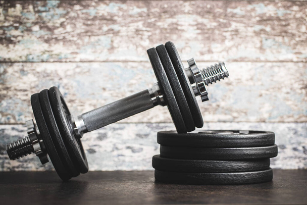 Iron dumbbells before old wooden wall. - Photo, image